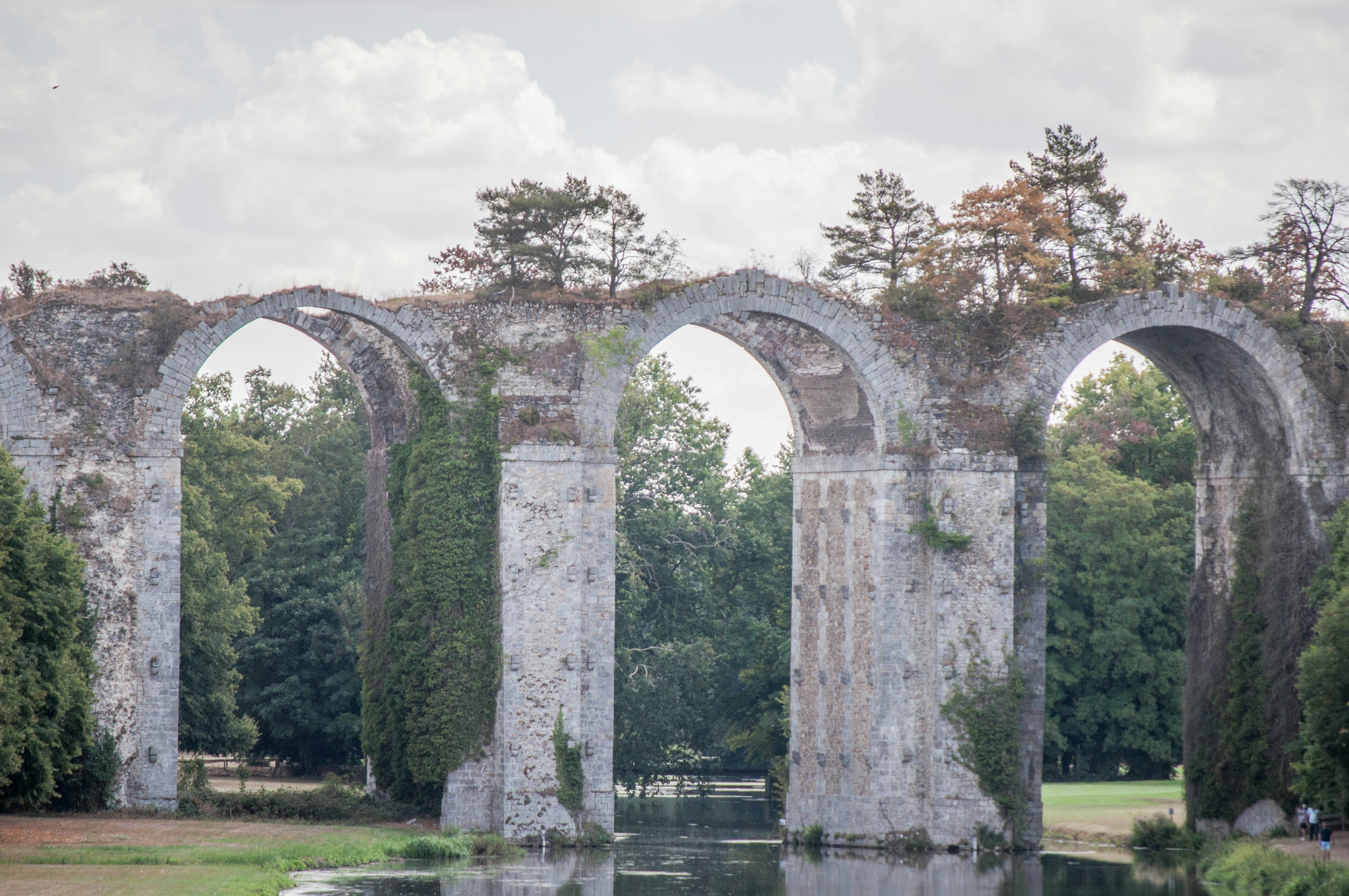 gray concrete bridge over river under white clouds during daytime